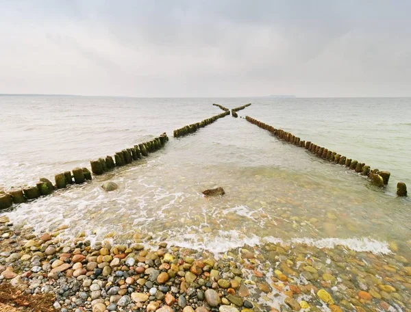 Buhnen aus Holz an der Ostseeküste mit einer Sonne, die in niedrigen Wolken versteckt ist. — Stockfoto