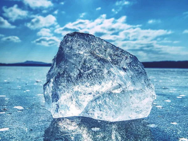 Eisscholle an gefrorener Oberfläche mit vielen Spiegelungen, blauer Himmel im Hintergrund. — Stockfoto