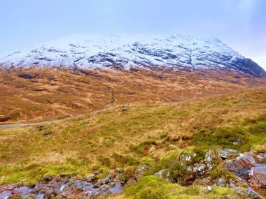 Dere dere akan su granit taşların üzerinde temizleyin. Ağır bulutları içinde karlı dağlar