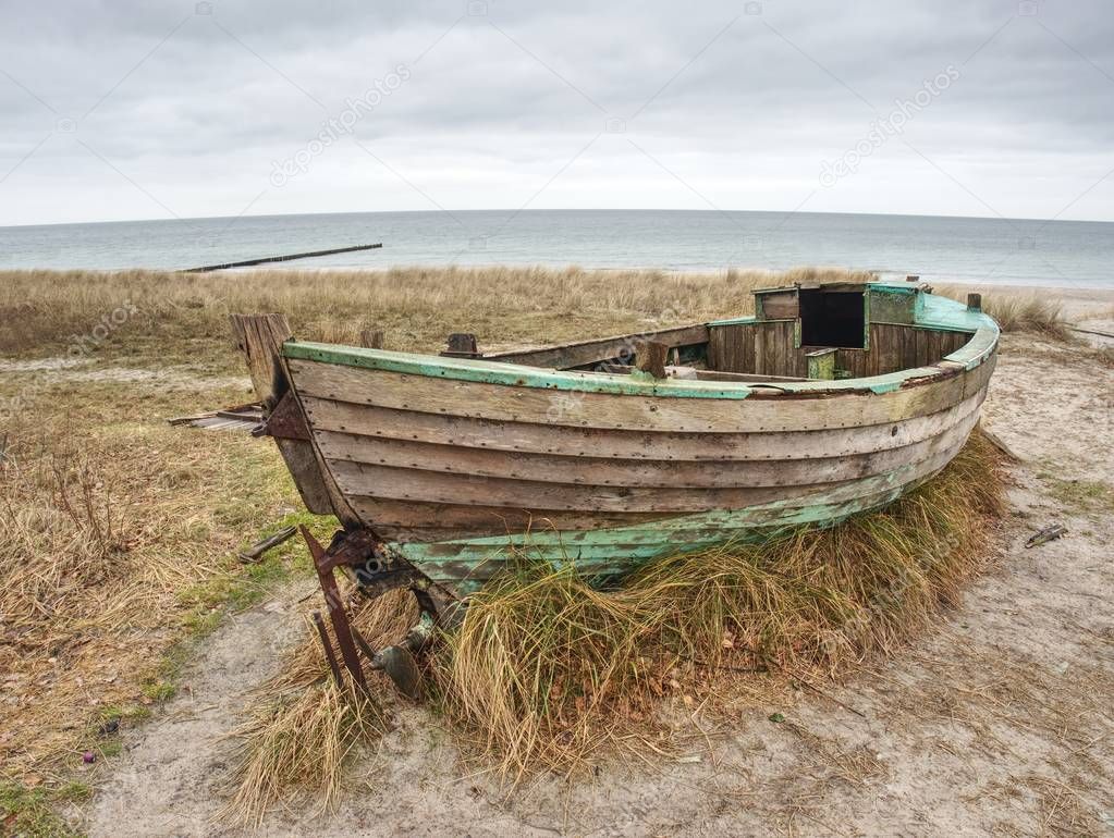 Abandoned wrecked boat stuck in sand. Old wooden boat on the sandy shore 