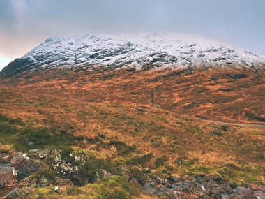 Dağlar manzara vahşi akışı önünde. Karlı dağ zirveleri ve gri bulutlar beyaz
