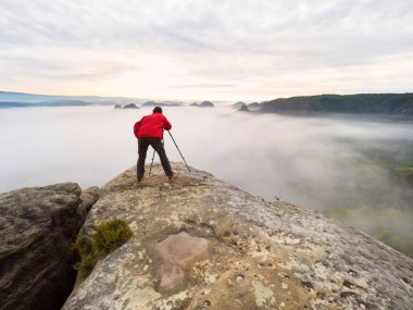 Fotoğrafçı siluet bir bulutlar deniz, Puslu dağlar yukarıda