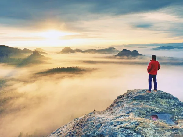 Vista posteriore al viaggiatore stand alone sulla scogliera con nebbia soffietto gambe, sole nel cielo nuvoloso — Foto Stock