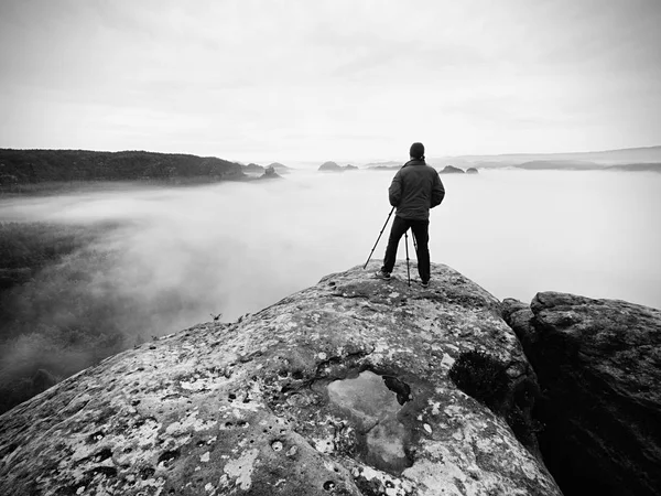 Fotógrafo artista trabaja con trípode en acantilado por encima de las nubes. Paisaje de ensueño fogy , — Foto de Stock