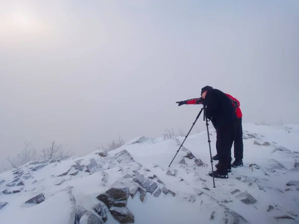 Dos hombres disfrutan del invierno fotografiando en montañas nevadas. Fotógrafo de naturaleza — Foto de Stock