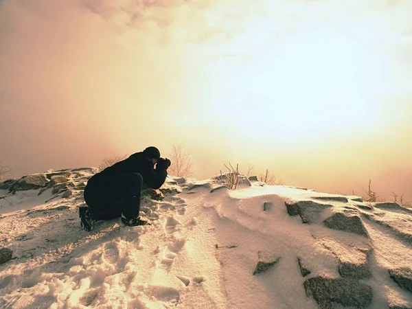 Photographer lay in snow on mountain peak and takes a picture of fantastic landscape — Stock Photo, Image