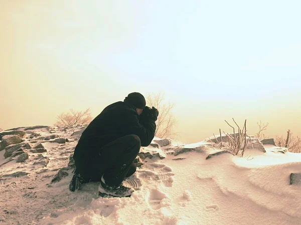 男は凍結秋の夜明けの写真を撮る、粉の雪と岩. — ストック写真