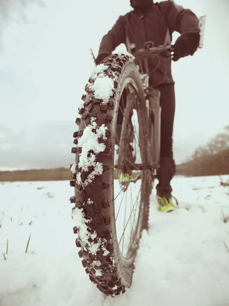 Hombre con bicicleta de montaña en la nieve. Camino perdido en la deriva de nieve. Detalle rueda delantera . — Foto de Stock