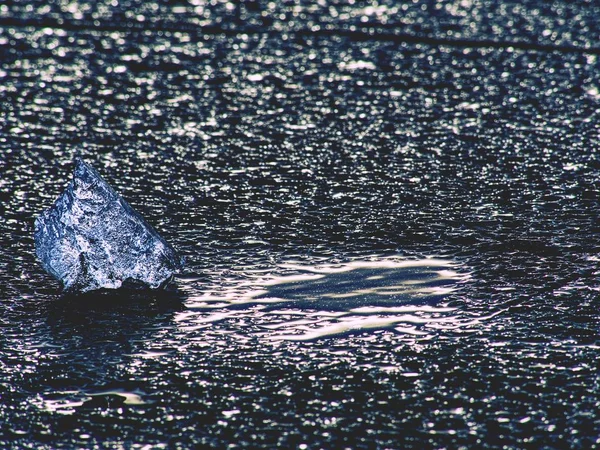 Голубой лед плавает на темно-сером или черном льду песчаного пляжа. Сильный ветер ломает айсберги — стоковое фото