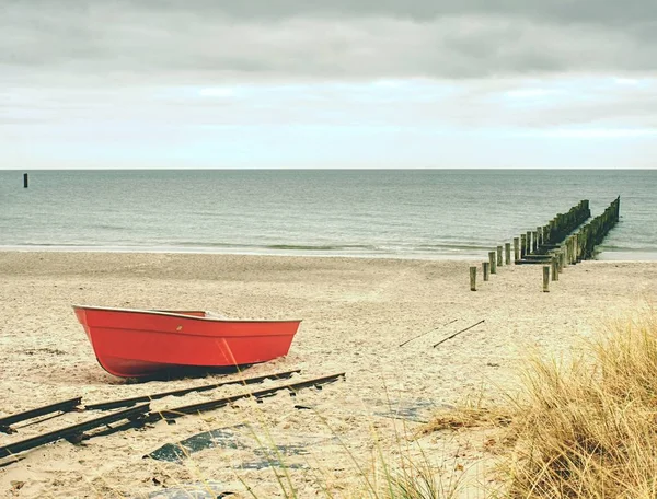 Abandoned red paddle boat on sandy beach of sea.  Smooth water level — Stock Photo, Image