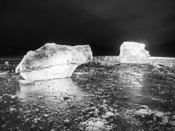 Cubos de gelo em um solo escuro reflexivo. Pedaços brilhantes de gelo picado e flocos de neve — Fotografia de Stock