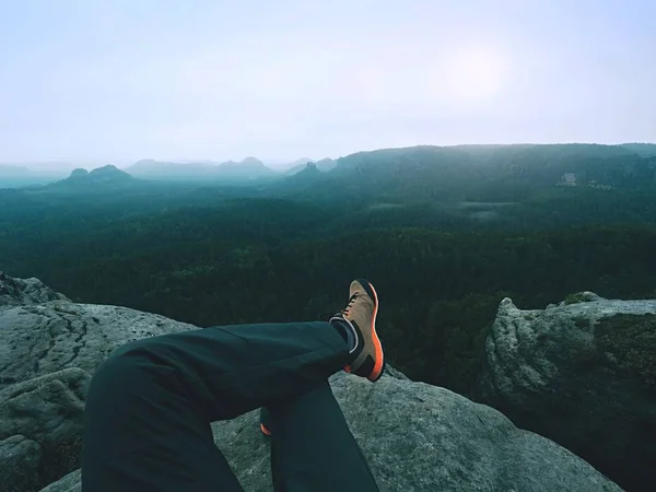 Jambes d'un homme sur le rocher. Randonneur reposant dans des bottes pour la montagne — Photo