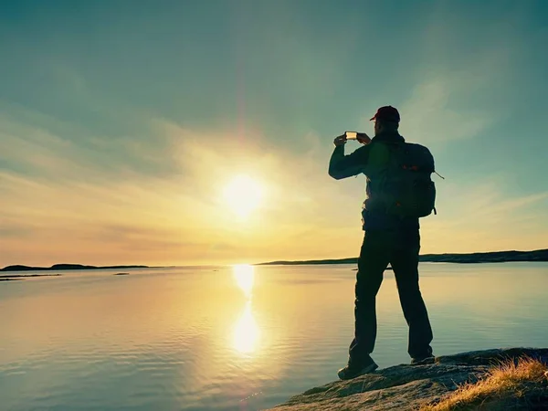 Alto turista prendendo selfie su cellulare contro vista panoramica del mare contro cielo serale. Specchio solare — Foto Stock