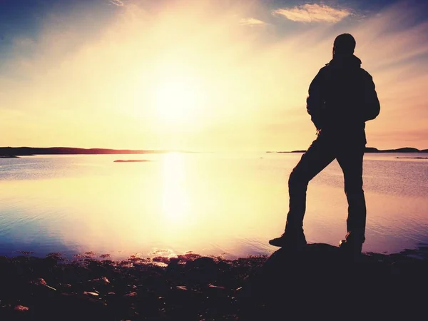 Yalnız adam doğru canlı günbatımı bakan silüeti. İşaret fişeği ve içinde yansıyan sığ sularda — Stok fotoğraf