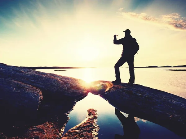 Sylwetka człowieka zachować wspomnienia z telefonu z aparatem w ręku. Cudowny zachód słońca na morzu — Zdjęcie stockowe