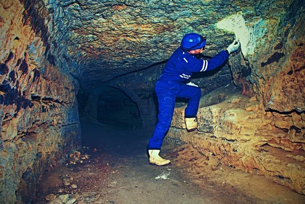 Trabalhador no túnel. Os funcionários em um terno protetor verificam sedimentos na parede rochosa — Fotografia de Stock