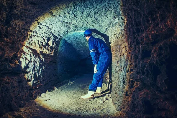 Staff do job in natural underground dome. Man with the illuminated headlight looks