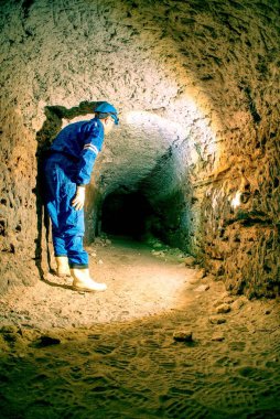 Workerman kask ve koruyucu elbise glowes ve güçlü kafa lambası kullanarak. Adam iş
