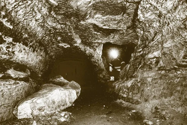 Hombre minero bajo tierra en un túnel minero. Trabajador en overol, casco de seguridad — Foto de Stock