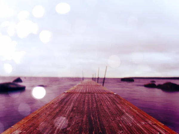 Efecto abstracto. Muelle de madera mojado en agua lisa de la bahía de mar. Antiguo lunar anclado con postes de acero — Foto de Stock