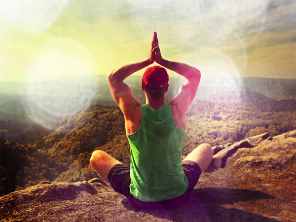 Efecto abstracto. Hombre sentado en la cima de la montaña en pose de yoga. Ejercicio yoga con una vista impresionante — Foto de Stock