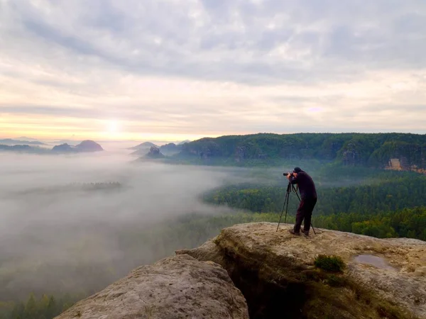 Fotograf auf dem Krater. Mann auf Gipfel über dicken Wolken, dunkles Regenwetter — Stockfoto