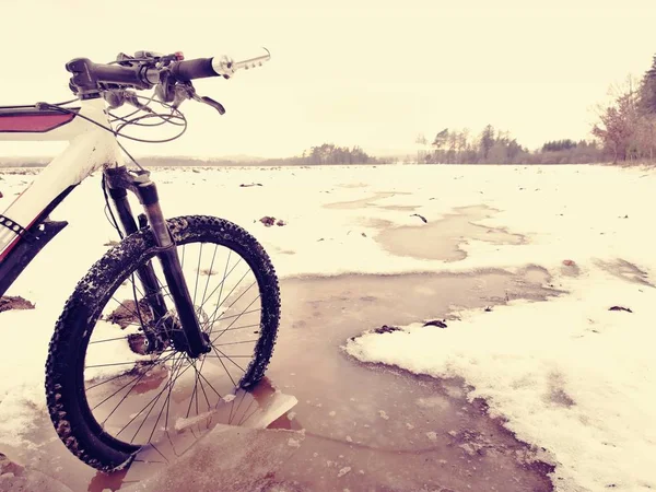 Mountain bike hjul bröt igenom is i vatten. Njut av vinter cykling med roliga — Stockfoto