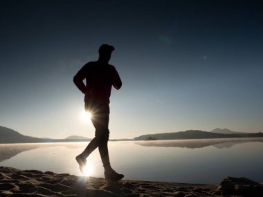 Geç öğleden sonra boyunca sahilde koşu adam. Genç kas yapı adam 