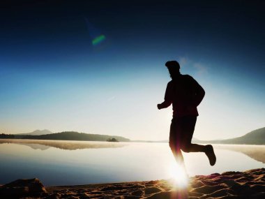 Geç öğleden sonra boyunca sahilde koşu adam. Genç kas yapı adam 