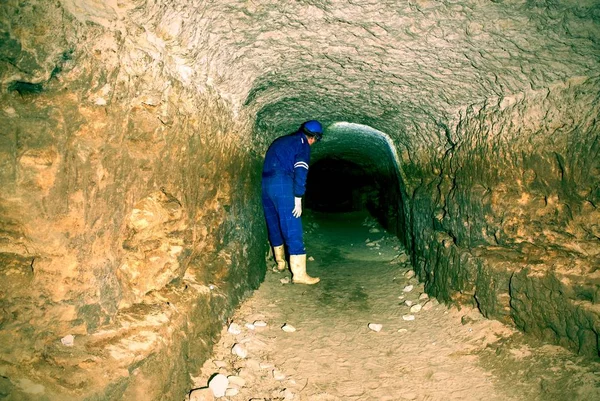Man works in mystical ancient long tunnel from orange sandstone walls, city underground. — Stock Photo, Image