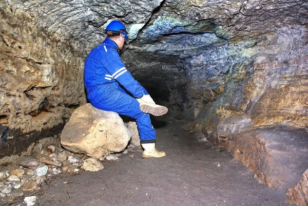 Hombre minero bajo tierra en un túnel minero. Trabajador en overol, casco de seguridad —  Fotos de Stock