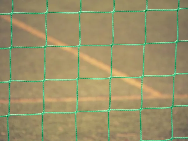 Zavřít detail fotbalové sítě proti zelené trávy na zamračený den. — Stock fotografie
