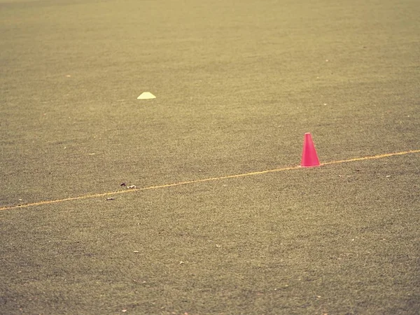 Jasně červené plastové kužel na natřené bílou čáru fotbalové hřiště. Hřiště fotbal zelené — Stock fotografie