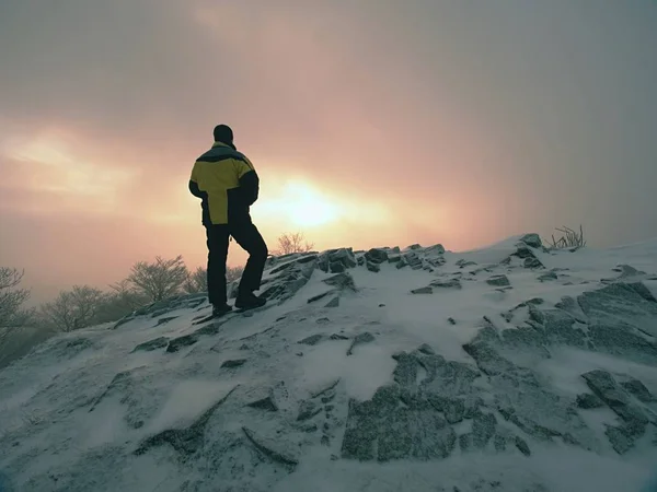 Hochgewachsene Wanderer in Schwarz auf dem Gipfel der Welt. Schwerer orangefarbener Nebel im Tal. — Stockfoto