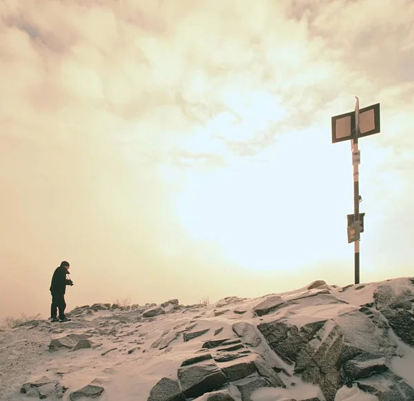 Alto escursionista in nero sulla vetta del mondo. Forte soffietto di nebbia arancione nella valle . — Foto Stock