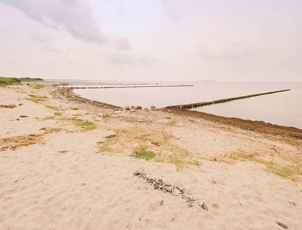 Oude houten golfbrekers op een kust van de Oostzee. Witte schuimende water spatten stenen — Stockfoto