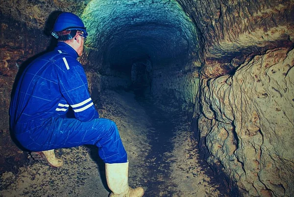 Hombre en oscuro túnel viejo, rodaje interior. Escaleras a túnel con paredes de piedra naranja . — Foto de Stock