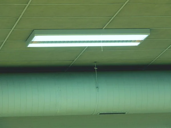 Open office hall ceiling with air pipe and lighting equipment.