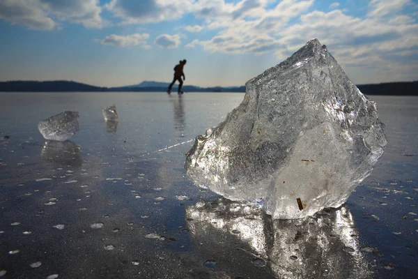 Faixa de gelo na superfície congelada do lago com reflexão. Homem patinagem no gelo — Fotografia de Stock