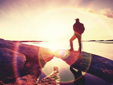 Deniz üzerinde kayalık uçurum açık giysili adam silüeti. Hikerthinking arka planda günbatımı sırasında. Dış görev kavramı seyahat.