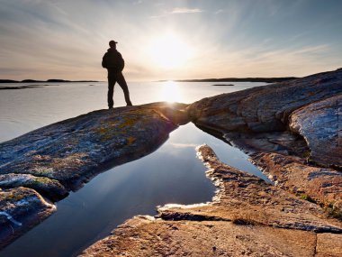 Seyahat etmek sırt çantası ile ayağa kayalık sahil ve güneş doğarken arıyorum. Kayalık clif