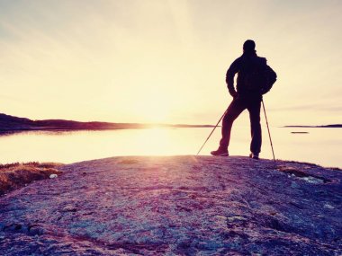 Yalnız adam doğru canlı günbatımı bakan silüeti. İşaret fişeği ve içinde yansıyan sığ sularda