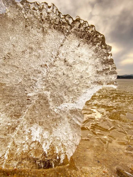 Il ghiaccio si scioglie sulla spiaggia sabbiosa. Dettaglio di lastra di ghiaccio con fessure profonde all'interno — Foto Stock