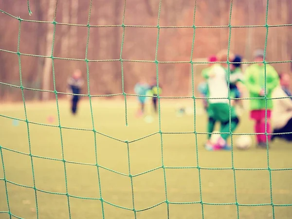 Football player stands against goal with net and stadium. Football gate net. Soccer gate