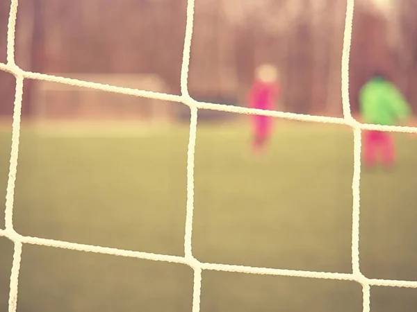 Soccer football net background over green grass and blurry stadium. Close up detail