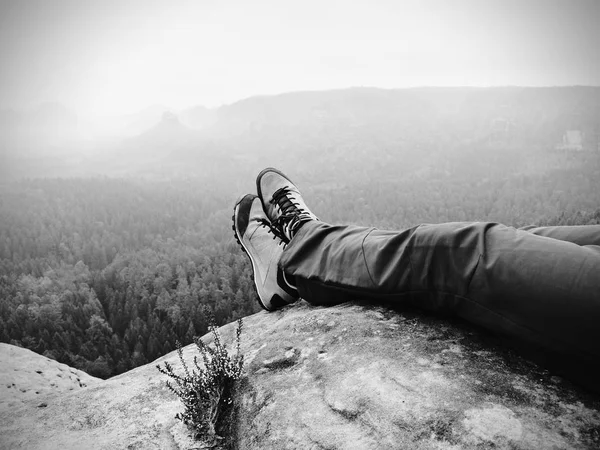 Las piernas del viajero en la cima de alta montaña en los viajes. Zapatos de trekking de cuero en pico — Foto de Stock