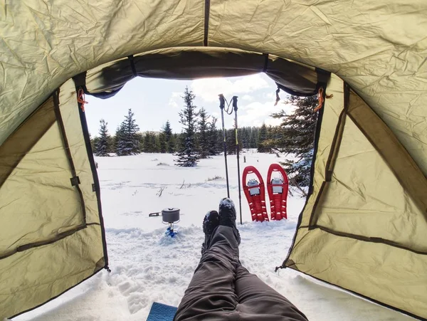 Hiker camping in winter mountains.  Man cooking food with portable gas cooker