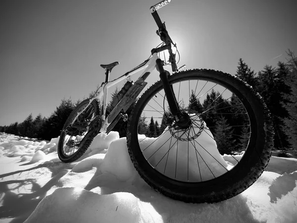 Bicicleta de montaña de pie en nieve congelada contra el cielo azul. Camino de asfalto oculto — Foto de Stock