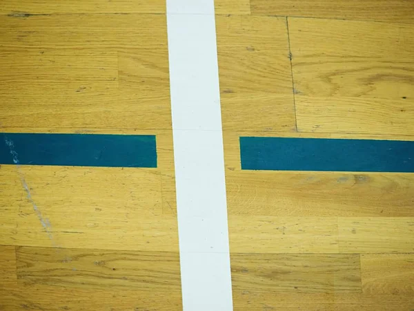 Hall floor in a gymnasium with crossed lines. Contour lines of basketball and handball playgrounds. Reflection in polyurethane varnish