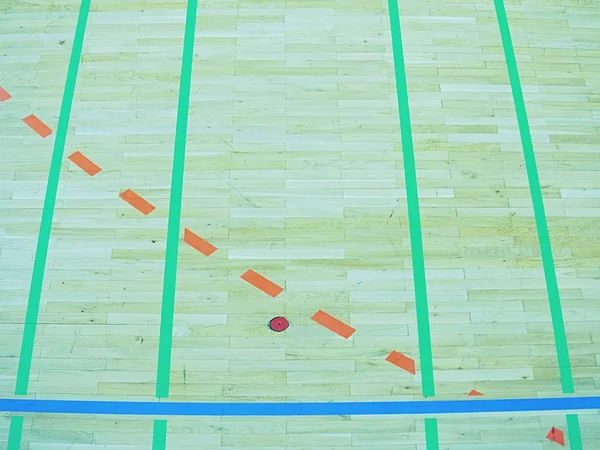Green shadows of shining floor of sports hall with marking lines and few scratches